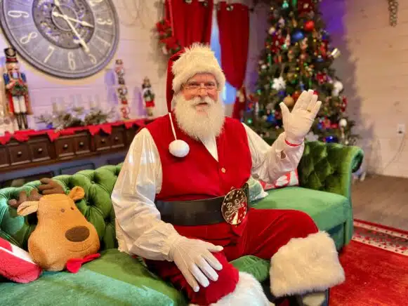 Santa's Jolly Lodge. Santa Waving, sitting on green couch.