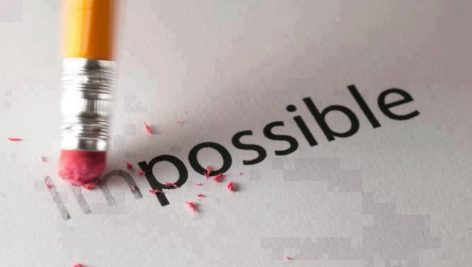 A pencil eraser erasing the "im" from the printed word "impossible"