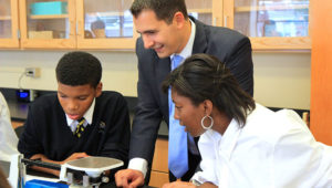 A man from the VWR Foundation watches students from Cristo Rey High School work in a lab donated by the Foundation