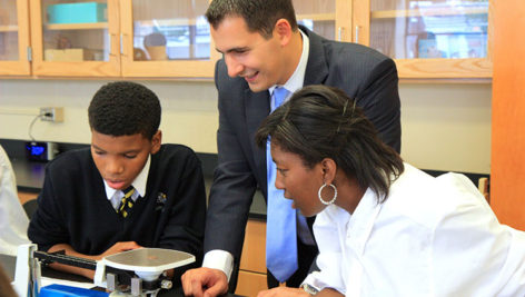 A man from the VWR Foundation watches students from Cristo Rey High School work in a lab donated by the Foundation