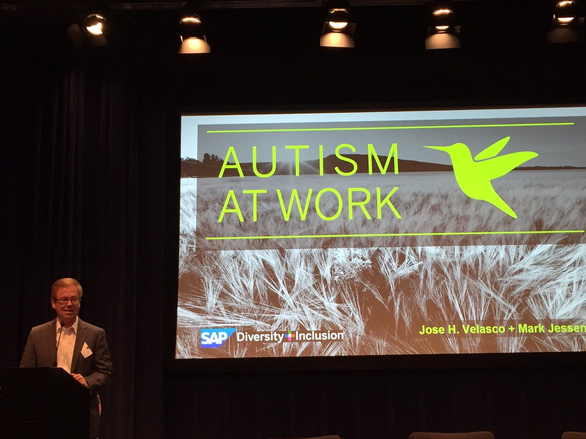A man next to a screen giving a presentation on the Autism at Work program.