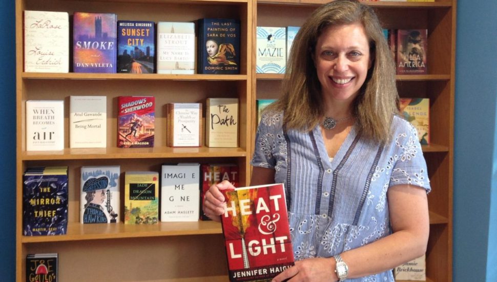 Cathy Fiebach holds a book in front of a bookcase.