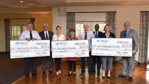 Township representatives hold big checks, donations from PECO