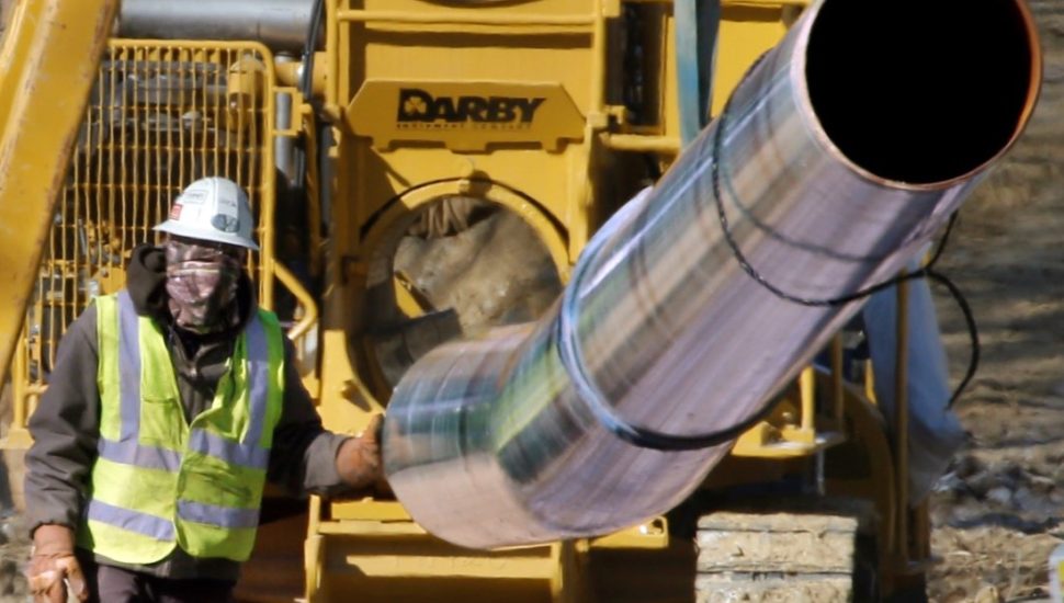 worker guiding a section of pipe