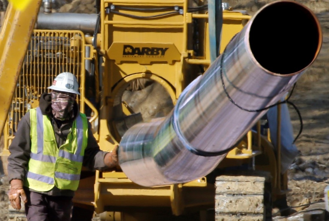 worker guiding a section of pipe