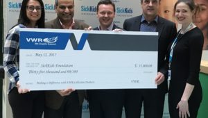 Several people holding a large check as the VWR presents a donation to the SickKids Foundation.
