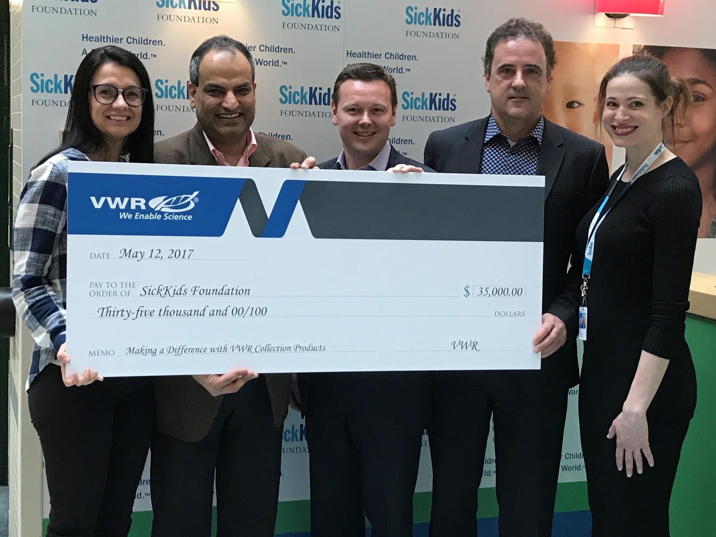 Several people holding a large check as the VWR presents a donation to the SickKids Foundation.
