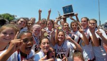 Members of the Archbishop Carroll girls lacrosse team hold up a trophy in victory.
