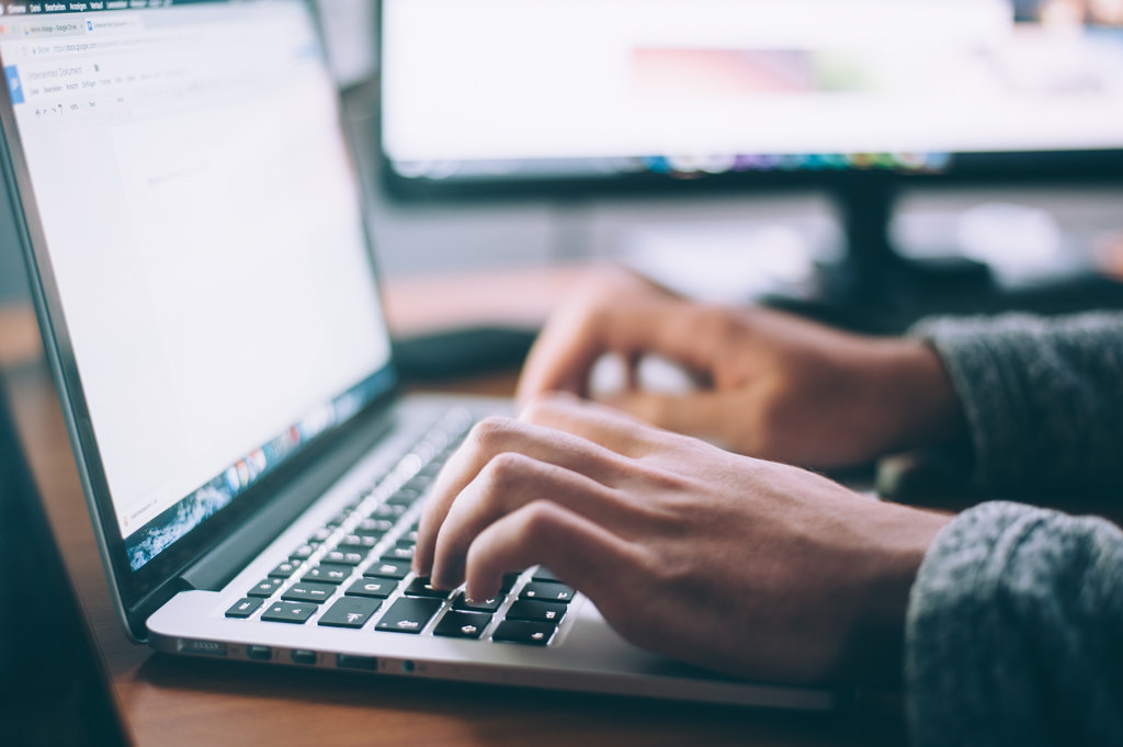 A man typing on a laptop computer.