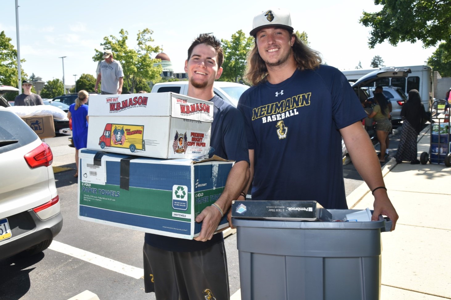 A picture of two young men carrying boxes and containers.