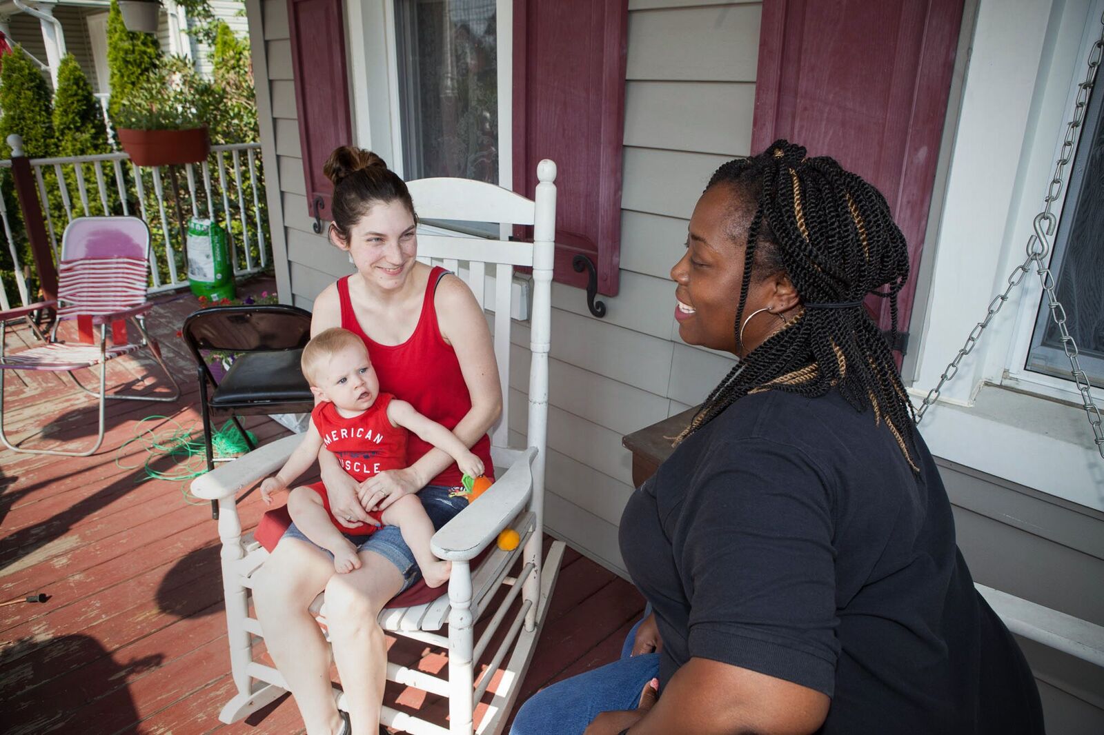 A mother holds her child while a woman speaks to them.
