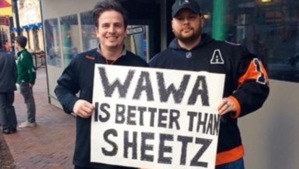 Convenience stores battle it out. Two men hold a Wawa is Better than Sheetz sign