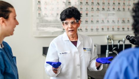 Dr. Sandra Weiss works in a Neumann University lab with students. She is retiring. They are dedicating a lab classroom to her.