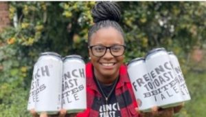 Charisse McGill holding cans of her French Toast Bites Ale