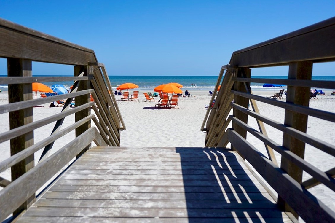 Wooden walkway and stairs leading to a sandy beach.