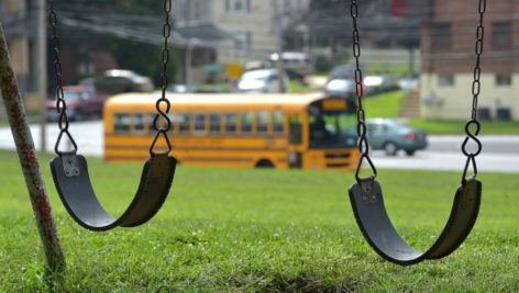 A swing set at Clifton fields with a school bus in the background.