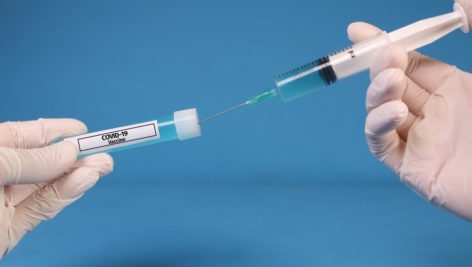 vaccine bottle and a hypodermic needle used at vaccination clinics.