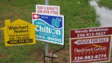 Several signs advertising homes for sale. Home prices are dropping.