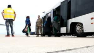 Afghan refugees board an airport bus.