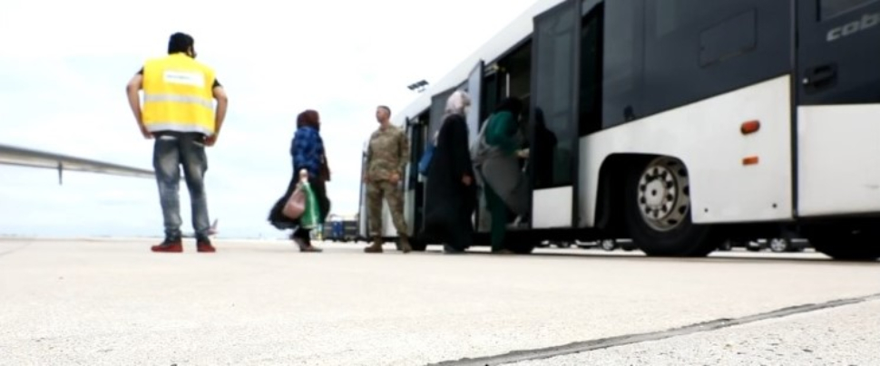 Afghan refugees board an airport bus.