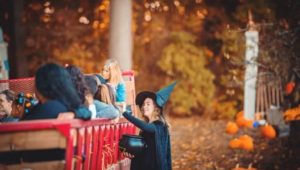 A woman dressed as a witch talks with kids on a hayride.