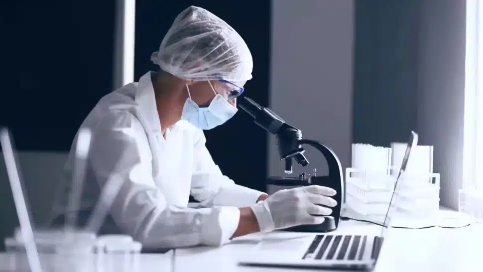A scientist looking into a microscope.