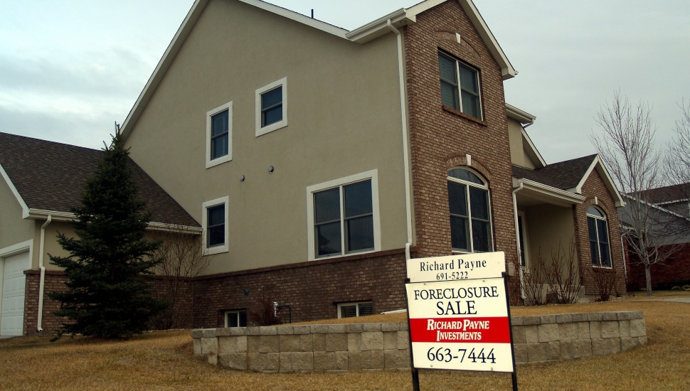 A house with a foreclosure sign in the yard.
