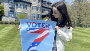 Jennifer Lambert holds a poster of her book cover for "Voter Z."