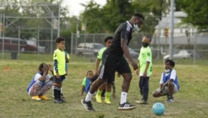 SWAG coach Nick Biggs works with Philadelphia youth on some soccer moves.