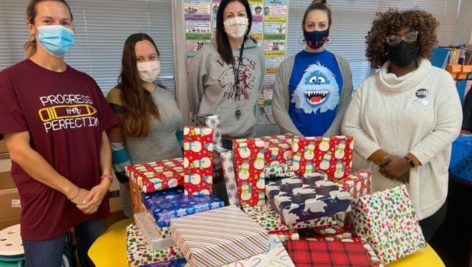 Teachers stand behind wrapped gifts for students at the Widener Partners Charter School in Chester