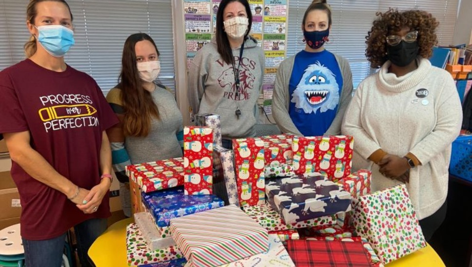 Teachers stand behind wrapped gifts for students at the Widener Partners Charter School in Chester
