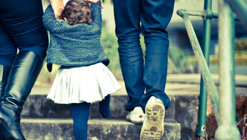 A man and woman with an infant walking up steps seen from behind.