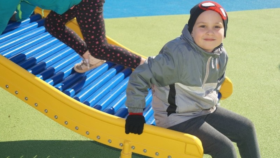 Little boy tries out a slide at Milestone Playground.