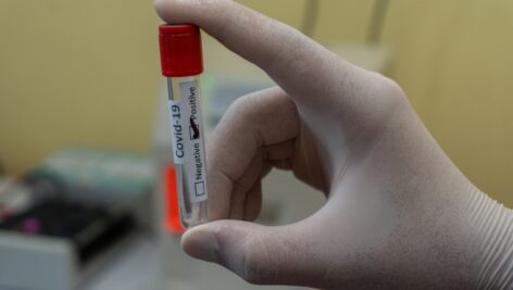 A hand holding a COVID test tube.