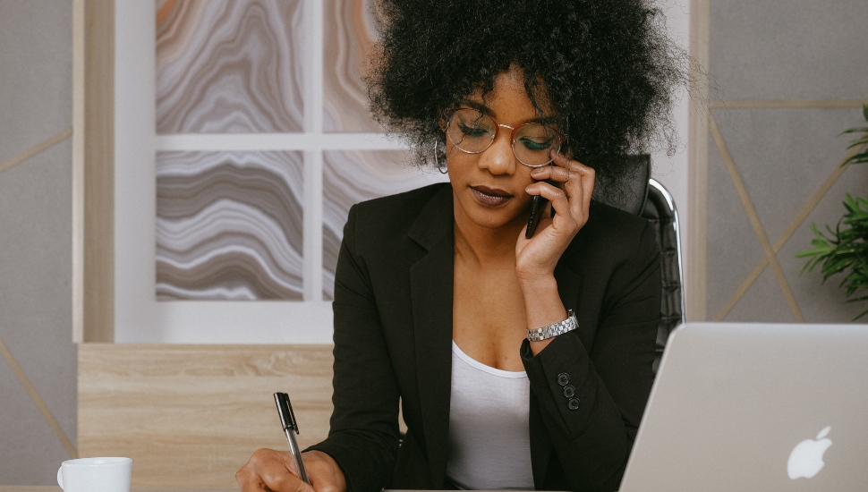 woman in black blazer holding smartphone.