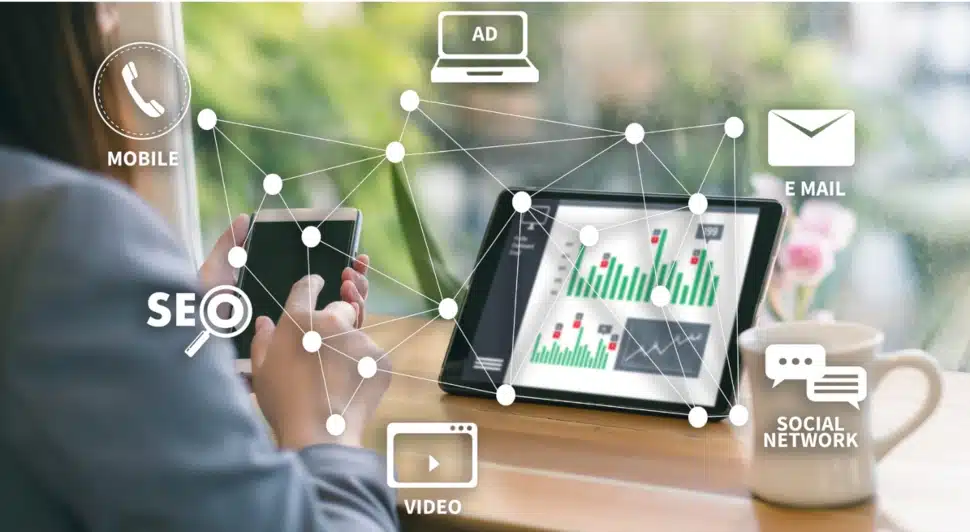 A man at his desk in front of a laptop surrounded by marketing images.