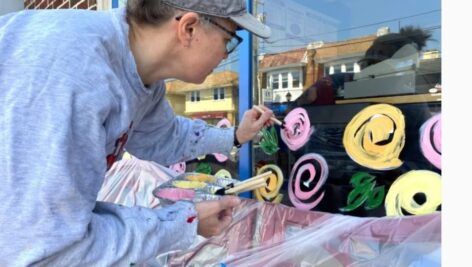Becky O'Hara paints a window along Brookline Blvd.