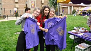 3 Women show off some West Chester University 150th anniversary T-shirts.