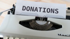A piece of paper in a typewriter that has the word "donations' typed on it.