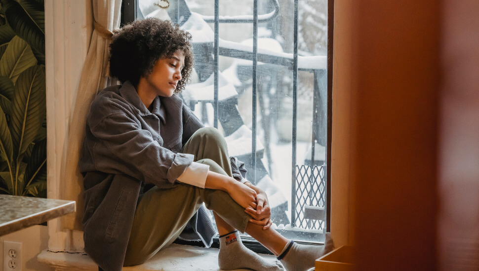 Woman reflecting on her life sitting in a window