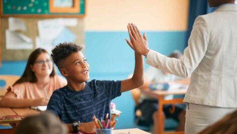 A teacher high-fives a student. CCRES provides behavioral health job options to qualified candidates.