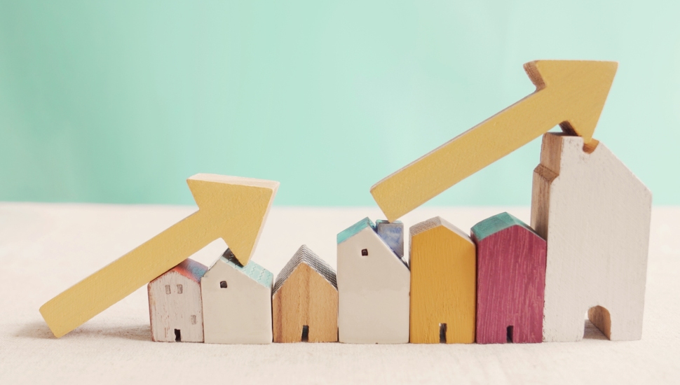 wooden houses with yellow arrows pointing up showing the rising price of homes.
