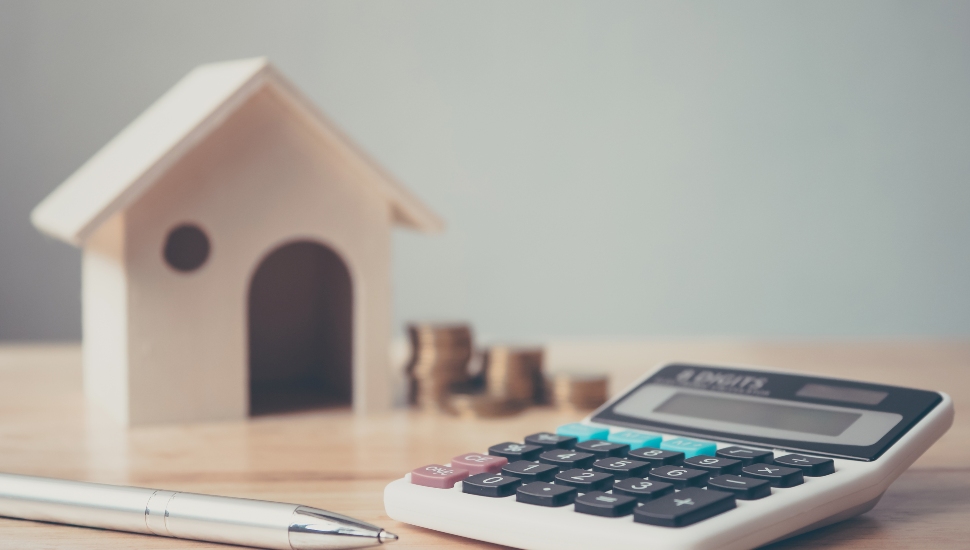 A little wooden house, a calculator and some coins to denote wealth in Delaware County