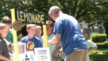 Man buying lemonade from a group of kids at a lemonade stand