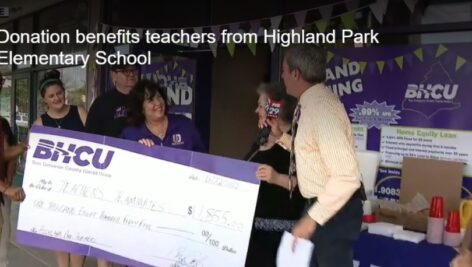 Teachers stand behind a giant check from BHCU.