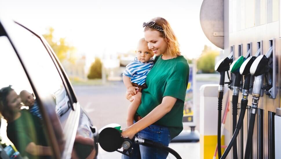 Woman holding a child pumping gas