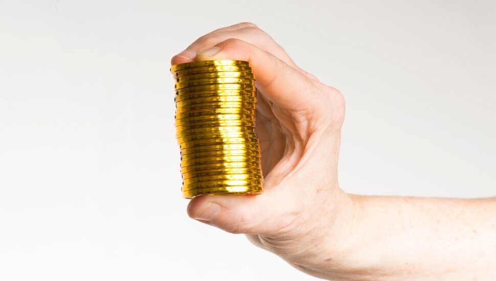 Someone holding a stack of gold coins in his hand