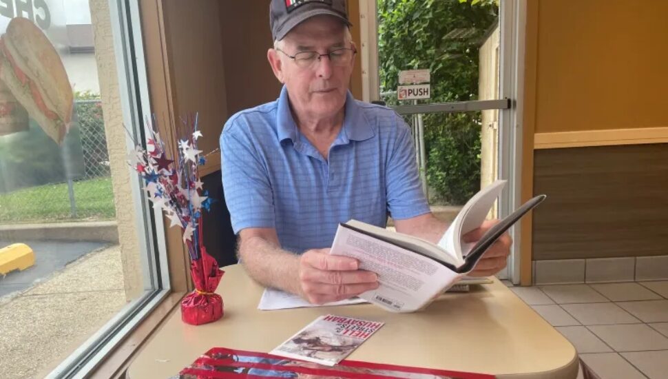Author and retired U.S. Marine David E. Kelly of Springfield looks through his book.