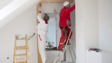 Two workers painting the inside of a house