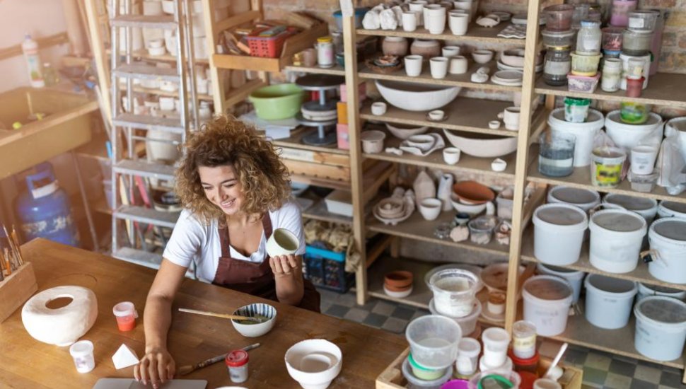 A woman at a table pursuing her hobby surrounded by arts and craft supplies